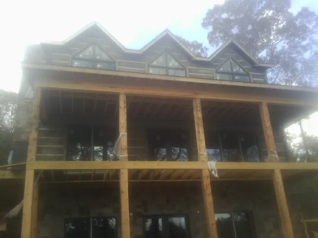 Dormers and porch framing on a large log home under construction — Roof Coating work by our crew in Laurel